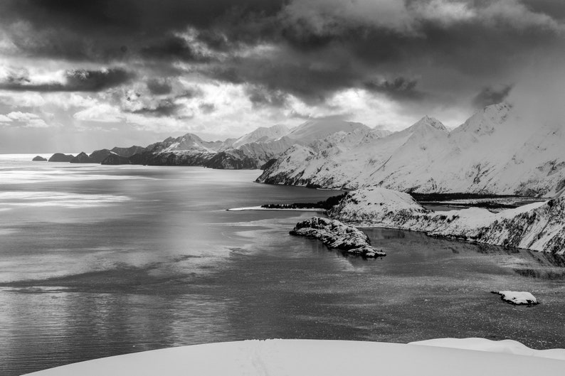 Aialik Bay and the Harris Peninsula, Alaska. Stormy skies over the Harris Peninsula in April, with snow still touching the ocean. Kenai Fjords National Park. Black and white.