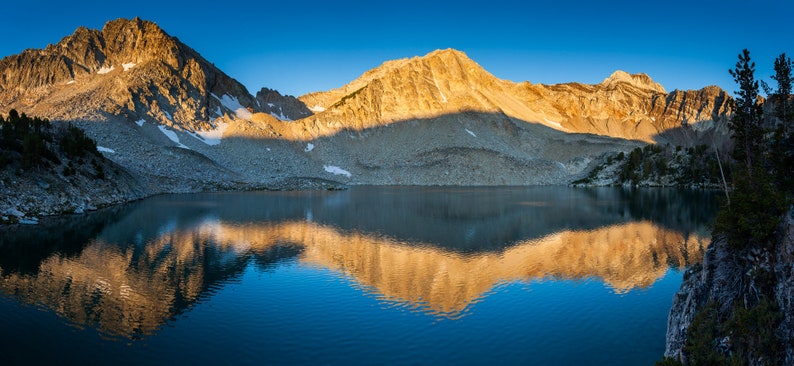 Golden Sunrise on an Alpine Lake. First golden light hits a high alpine lake.