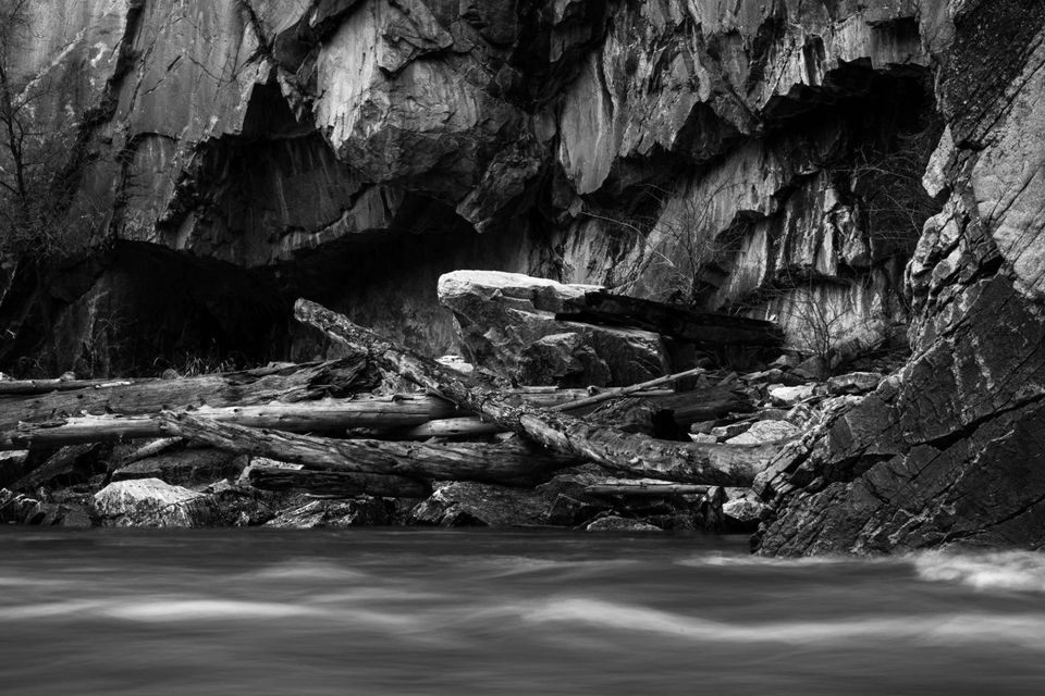 Riverside Detail. A slow shutter blurs the Middle Fork of the Salmon beneath a cliff wall rising above driftwood.
